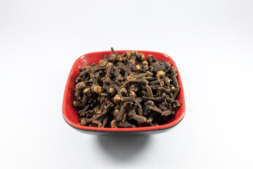 Pile of organic fresh whole clove buds in a bowl isolated on white background. close up.top view.