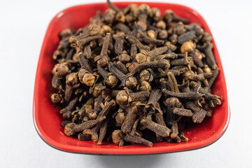 Pile of organic fresh whole clove buds in a bowl isolated on white background. close up.top view.