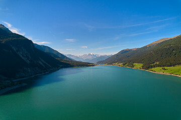 Aerial view of lake (Reschensee). Large reservoir surrounded by mountains at sunny noon. Recreation area for tourists and sportsmen. Italy, Vinschgau.