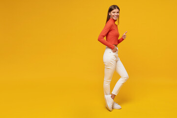 Fototapeta na wymiar Full length side view portrait of stylish woman showing thumb up gesture on yellow background
