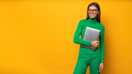 Portrait of woman hr specialist holding laptop on yellow banner background going to interview