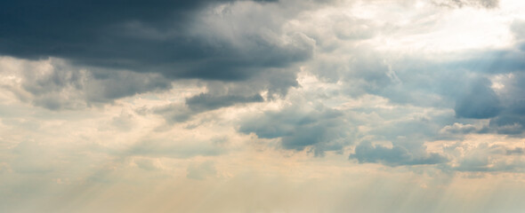 Dramatic Sky Background with sunny beams. Panoramic view of Stormy Clouds in Dark sky