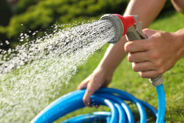 Man spraying water from hose in garden, closeup