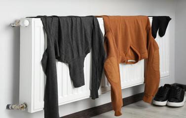 Heating radiator with clothes and shoes in room
