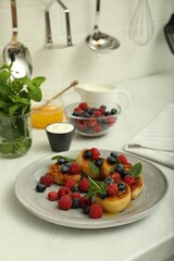Delicious cottage cheese pancakes with fresh berries and mint on white countertop