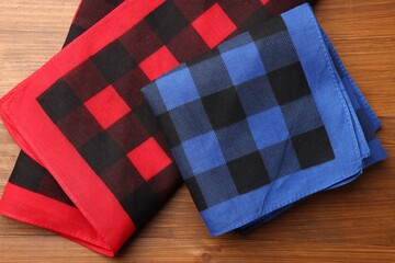 Folded red and blue checkered bandanas on wooden table, flat lay