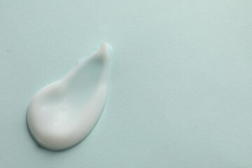 Sample of face cream on light blue background, top view. Space for text