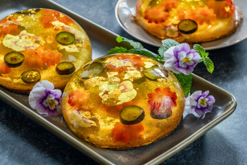 Lemon jelly globes with fresh fruit, edible flowers and gold flakes on pistachio biscuit - gourmet dessert