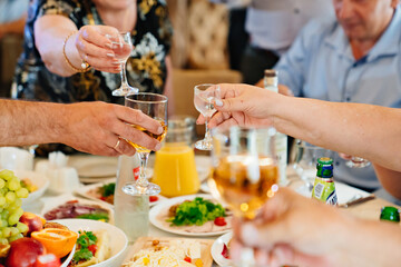 hands with glasses of drinks above the festive table. 