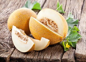 Cantaloupe melon with leaf and melon slice on old wooden table.