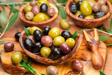 Kalamata, green and black olives in the wooden plates. Food background.