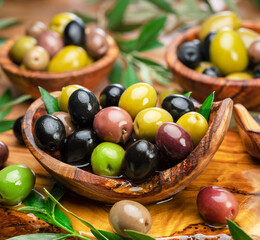 Kalamata, green and black olives in the wooden plates. Food background.
