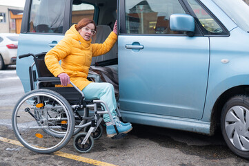 Fototapeta na wymiar Caucasian woman in a wheelchair gets into the car. 
