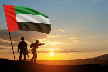 Silhouettes of soldiers with the flag of UAE against sunset or sunrise. Concept of national holidays. Commemoration Day.