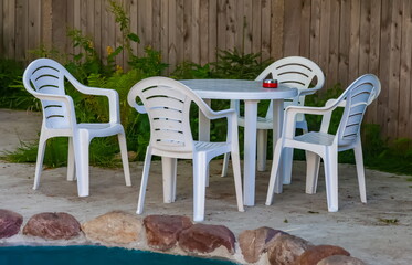 White plastic table and chairs on the background of a wooden fence