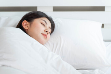 Beautiful young Asian woman sleeping in bed at home - good night sleep concept.