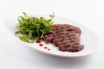 Ribeye steak with arugula on white plate