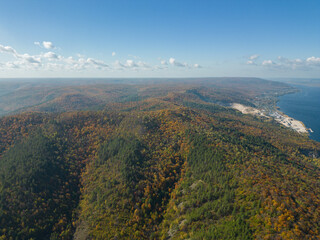 The concept of mountain tourism. A wide river along the forest mountains. Autumn colors of the mountains. Golden autumn in the mountains. Aerial photography. A photo from a drone.