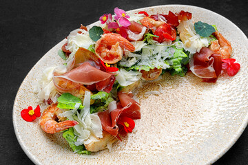 Salad with shrimp, prosciutto and cheese on a plate
