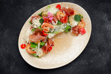 Salad with shrimp, prosciutto and cheese on a plate