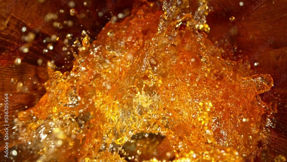 Poster super slow motion of pouring whiskey, rum or cognac inside the barrel. filmed on high speed cinema c