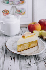 Apple cheesecake and tea pot on wooden table
