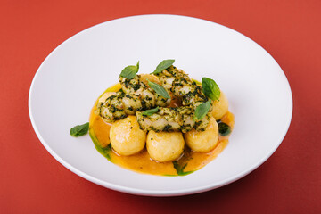 Baked fish fillet and potatoes on white plate