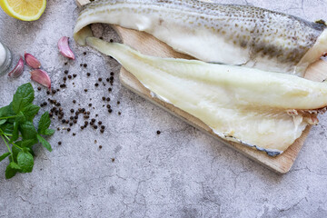 Fresh fish, raw cod fillet. Lies on a wooden board in the kitchen