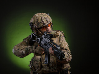Fototapeta premium a male soldier in military clothes with a weapon on a dark background