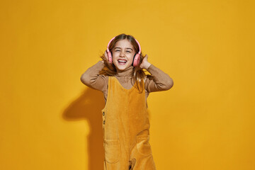 Laughing little girl listening music in headphones