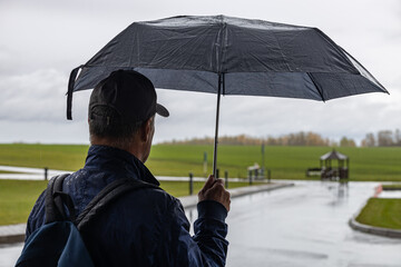  a man stands under an umbrella