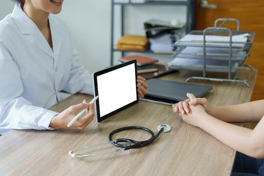 Asian female doctor holds computer tablet to customer, white screen can insert text or image