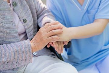 Fototapeta na wymiar シニア女性の手を握る介護士の手元