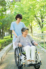 シニア女性の車椅子を押す女性医療従事者