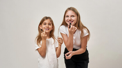 Two european girls painting lips with lipsticks