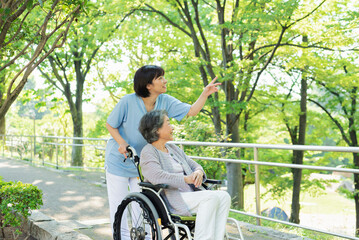 シニア女性の車椅子を押す女性医療従事者