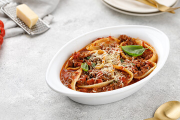 Pasta stuffed with bolognese meat sauce, tomatoes, cheese, basil in baking dish. Italian bolognese pasta with parmesan. Cannelloni, abissini.