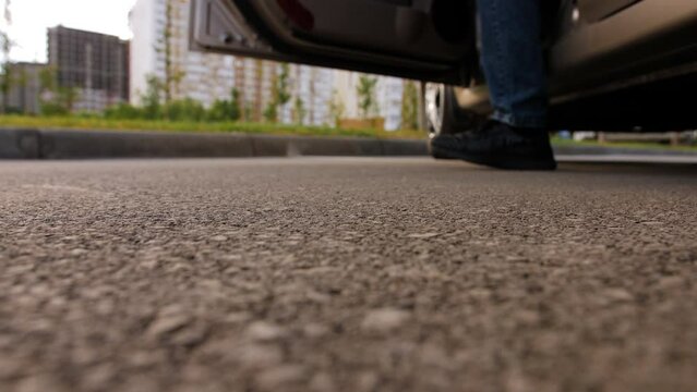 An irresponsible man gets out of the car and throws a plastic bag with various garbage on the asphalt.