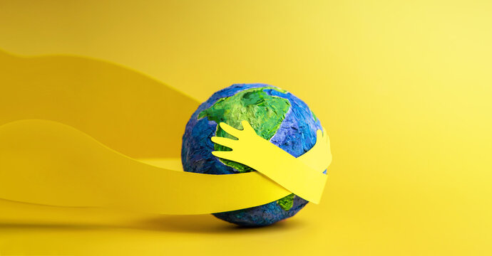 World Earth Day Concept. Green Energy, ESG, Renewable and Sustainable Resources. Environmental Care. Paper Cut as Hands Embracing Green Globe. Top View