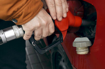 He takes out the fuel-refueling nozzle from the tank and closes the car's tank cap.
