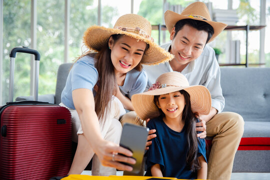 Young happy family asian father mother and daughter taking selfie photo exciting preparing luggage suitcase booking online ticket and hotel for vacation holiday travel trip