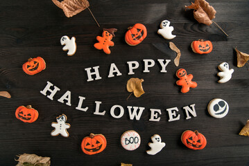 Mock-up Happy Halloween inscription.White and orange delicious ginger cookies, located on brown wooden surface. Top view