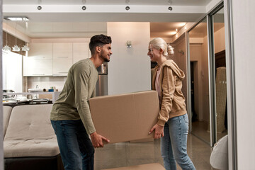 Fototapeta na wymiar Side view of couple carrying box in new apartment