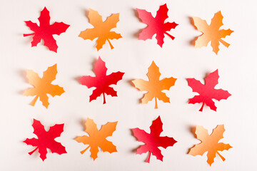 Fototapeta premium Orange and red cut out maple leaves from craft paper in rows. Autumn decoration.