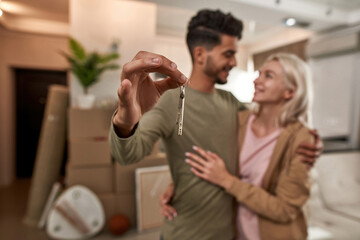 Keys in hand of man hugging girl in new apartment