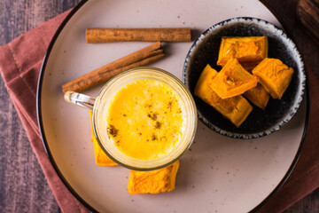 Pumpkin latte in glasses and pieces of pumpkin in a bowl. Homemade autumn drinks. Top view. Closeup