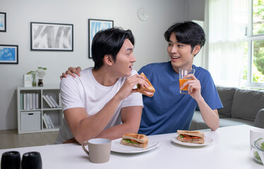 Young Asian male couple lifestyle living concept. Happy LGBT gay couple having breakfast together in the kitchen.