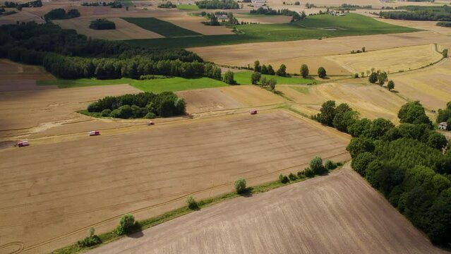 A group of tractors drive through farmlands, harvesting, farming. Aerial, Drone. 