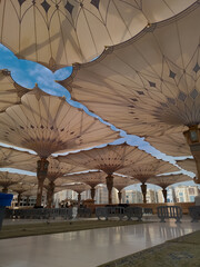 Medina, Saudi Arabia - October 07, 2022: Umbrella construction on the square of Al-Masjid An-Nabawi or Prophet Muhammed Mosque are protecting people from sun at daytime and work as lights at night