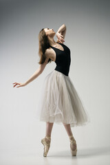 ballerina in a bodysuit and a white skirt improvises classical and modern choreography in a photo...